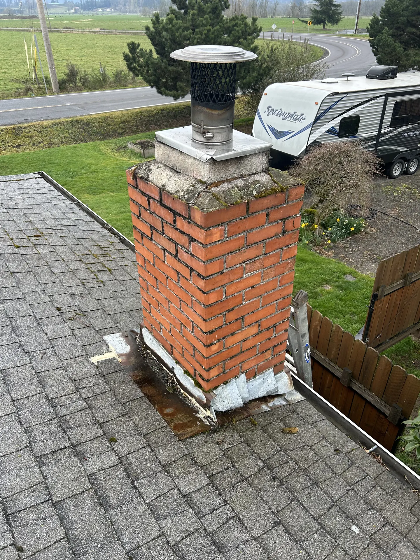The same Estacada chimney before the repoint: a mossy, cracked crown and failing step flashing