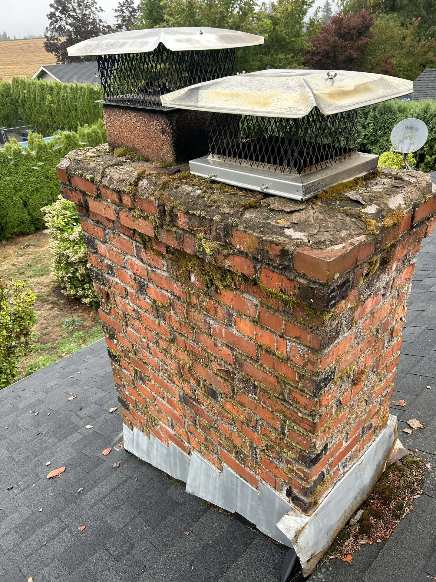 Moss-eaten chimney crown with rusted step flashing before the rebuild
